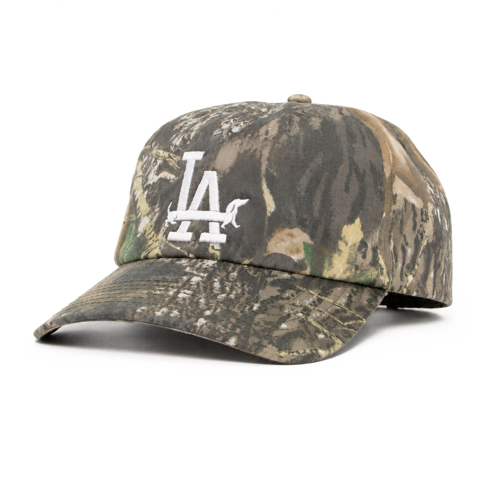Camouflage baseball cap by Bean Goods featuring a white embroidered 'LA' logo with a dachshund silhouette weaving through the letters.
